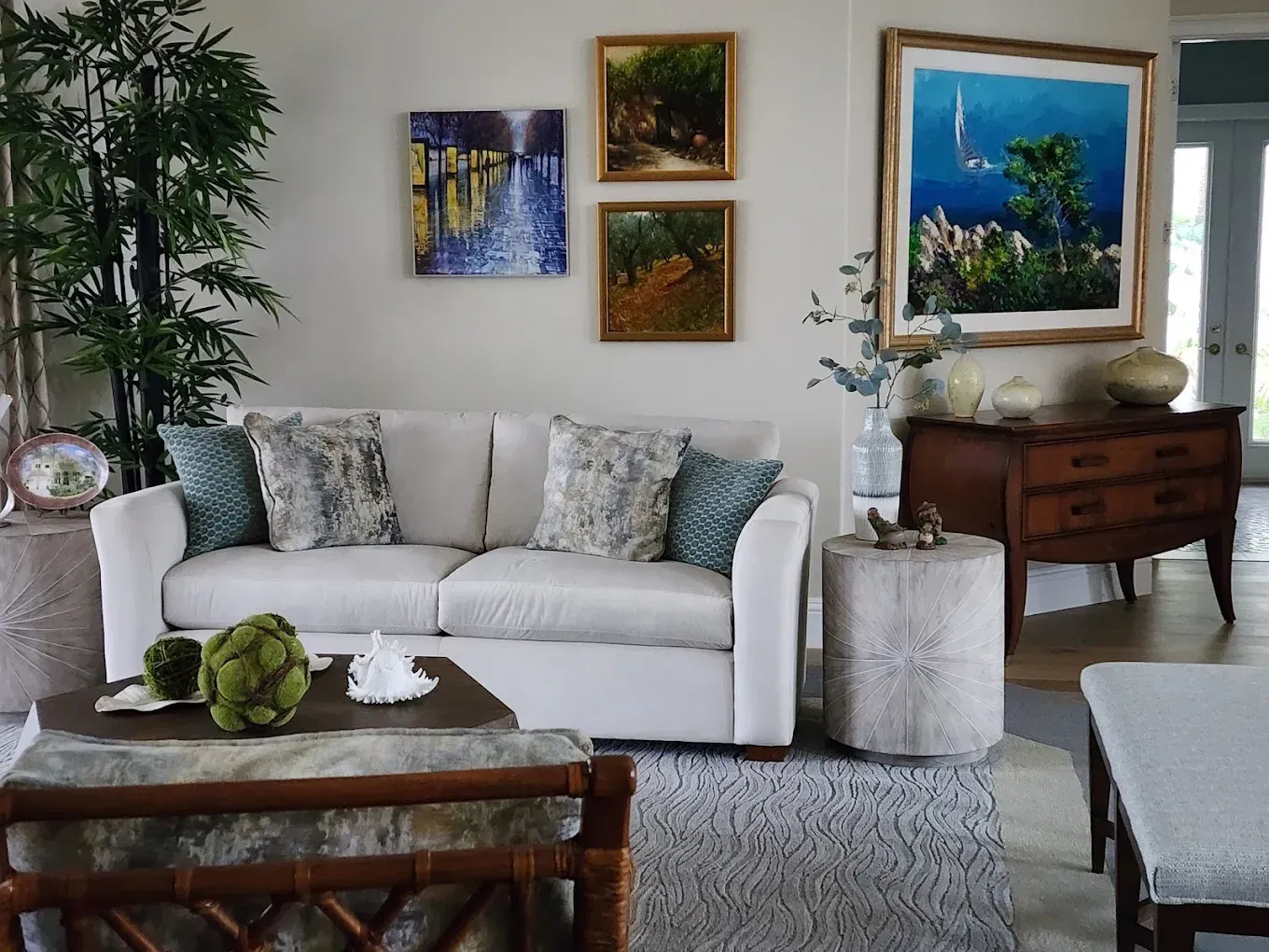 Cozy living room with white sofa, artwork, and bamboo. Light colors and natural textures create a relaxed atmosphere.