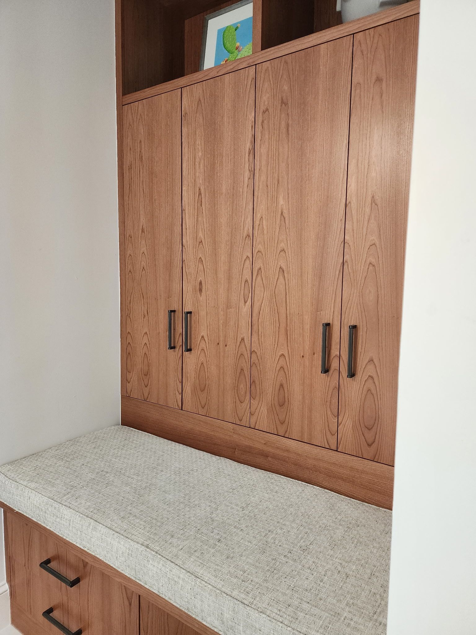 Built-in wooden cabinetry with upper doors, drawers, and a light-colored speckled countertop in a home interior.