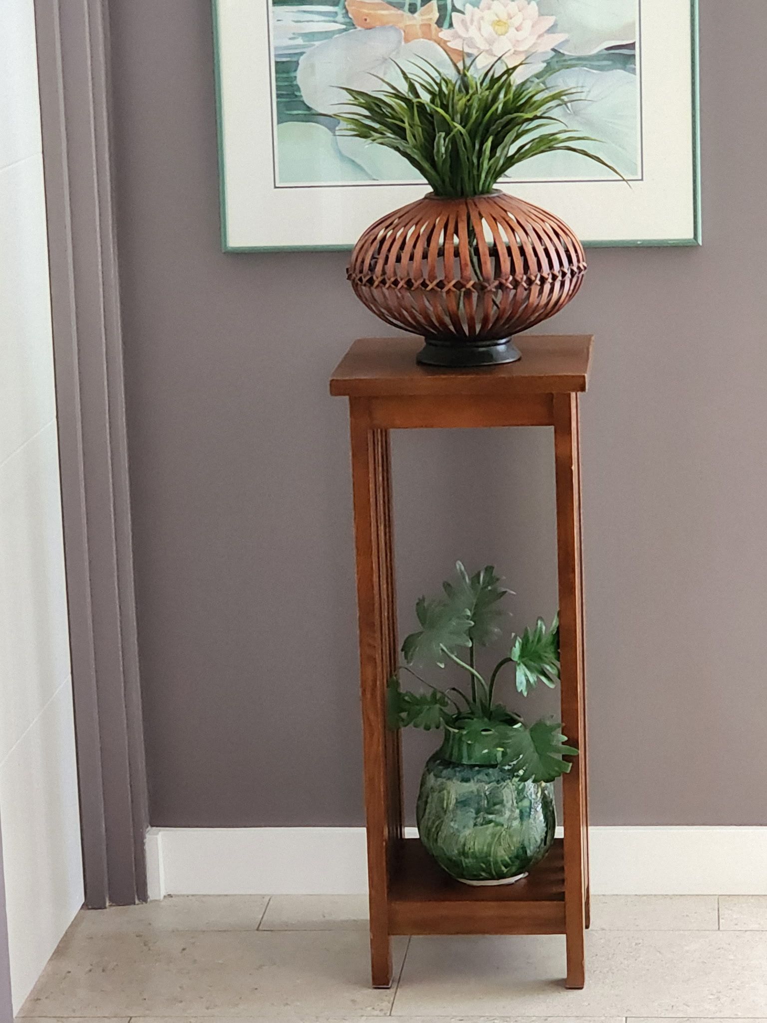 Wooden plant stand with two decorative pots. One holds a plant with green leaves, the other a plant with brown leaves.