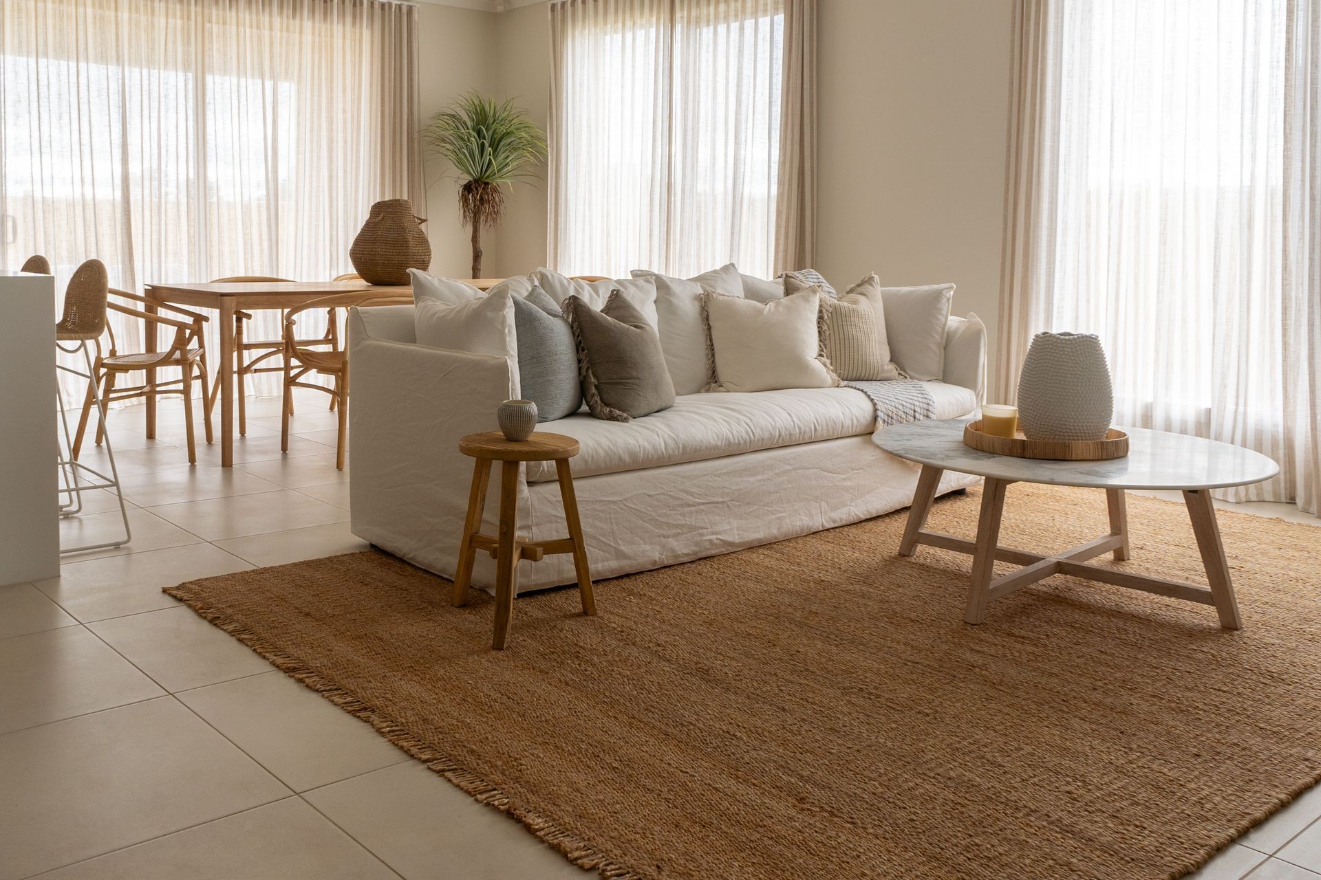 Coastal living room with white sofa, wood dining table, and sheer drapery near Fort Myers, FL