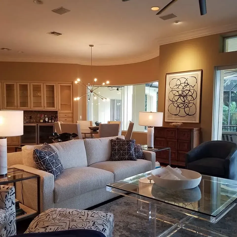 Living room with a beige sofa, glass coffee table, and abstract art.