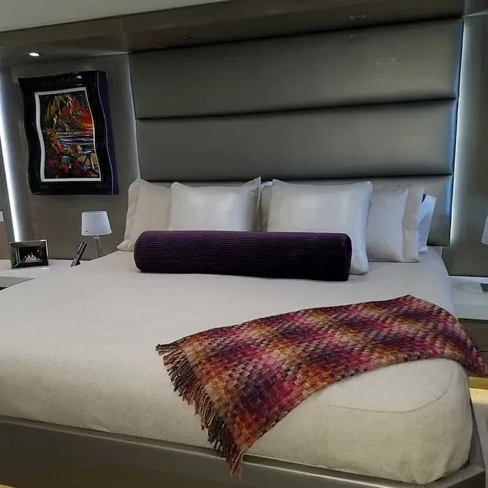 Bedroom with king-size bed, gray headboard, and colorful throw blanket. Artwork hangs on the wall.