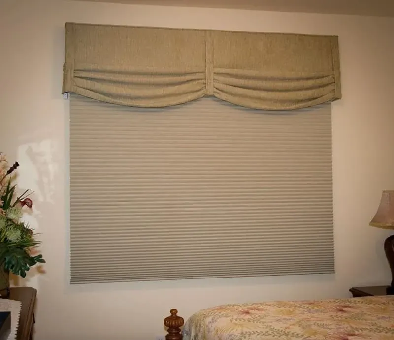 Window with beige pleated blinds and matching scalloped valance.