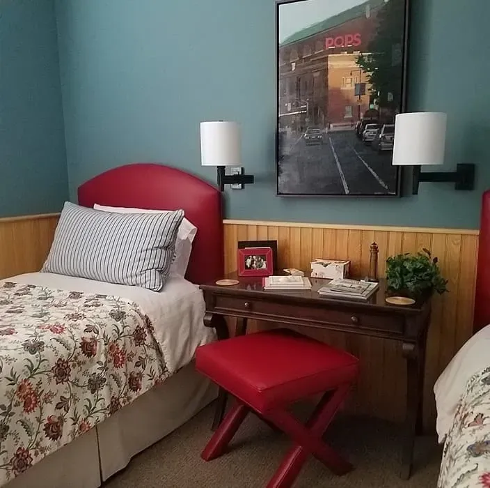 Twin beds in a room with red headboards, blue walls, a nightstand, and a painting.