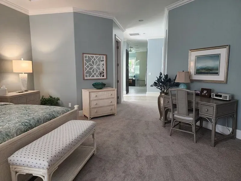 Bedroom with blue walls, carpet, furniture, and desk.