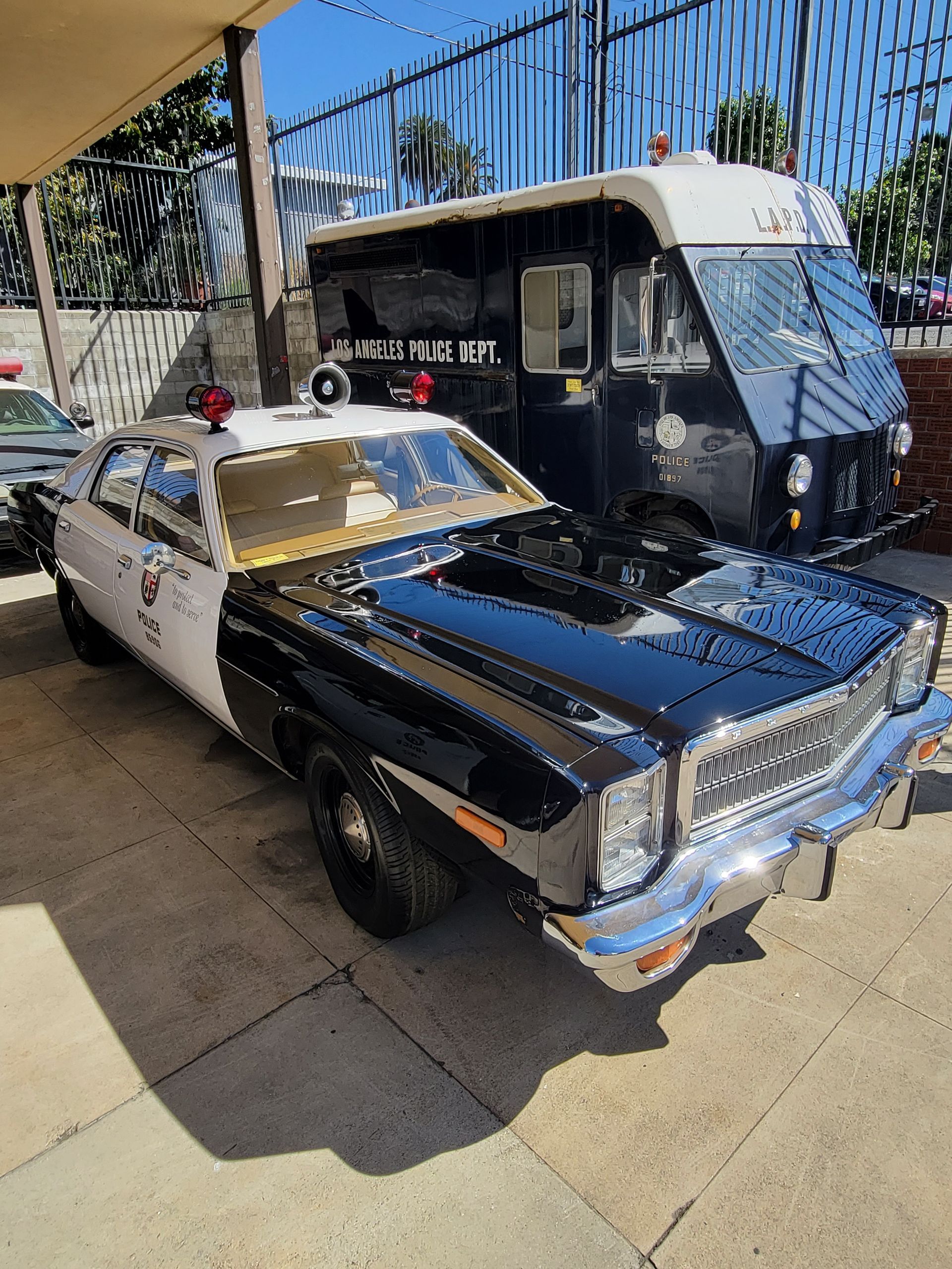 Black and white police car and dark food truck parked outside.