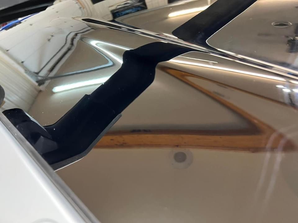 Black structural support on a reflective, polished surface, possibly inside a vehicle.