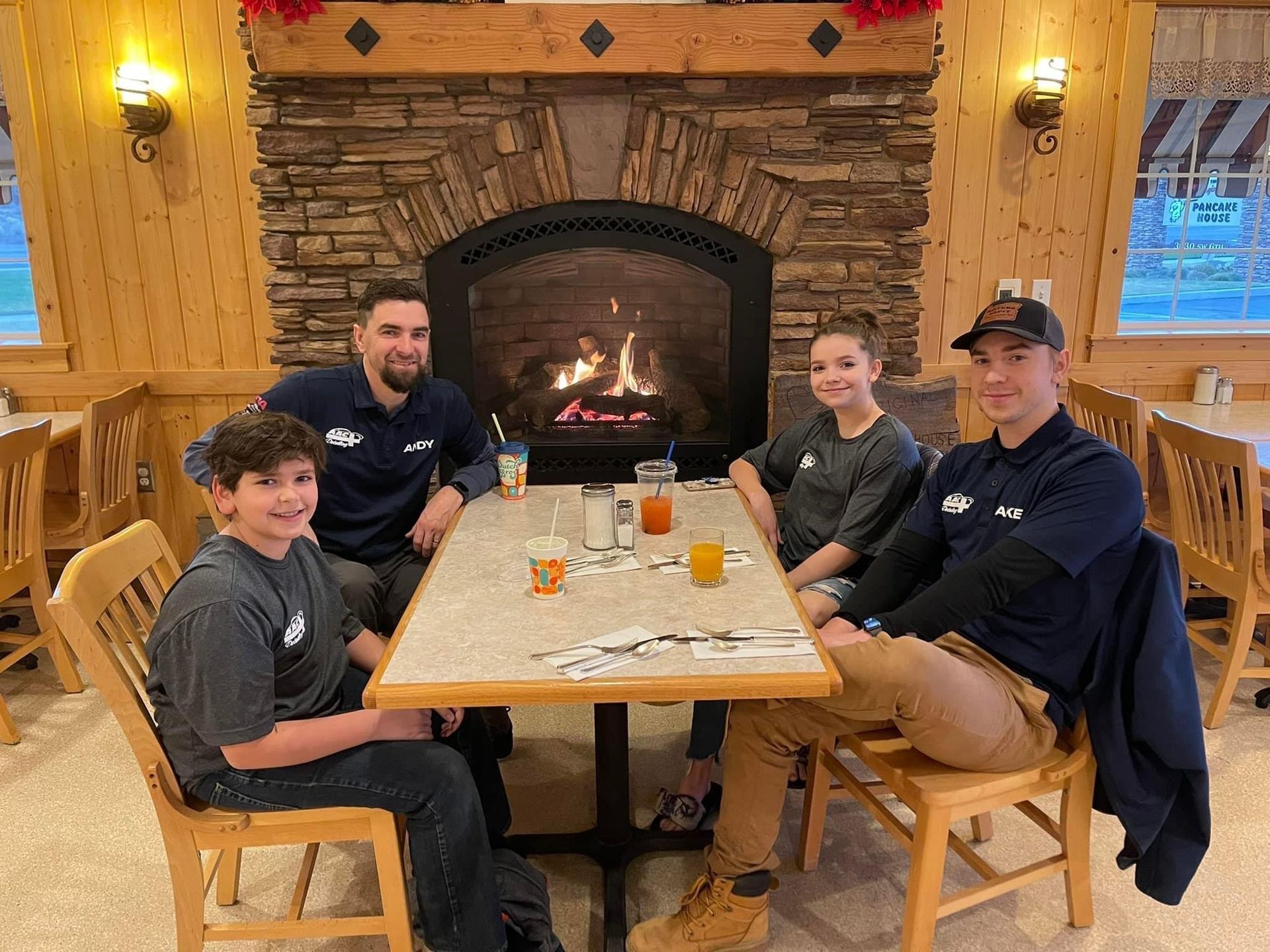 Family of four sits at a table in a restaurant with a fireplace.