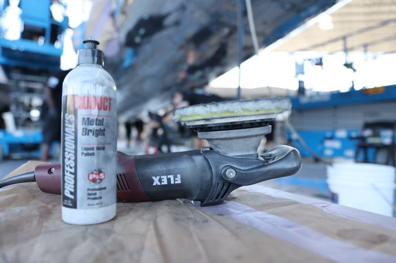 Bottle of metal polish and a power buffer on a boat's hull.