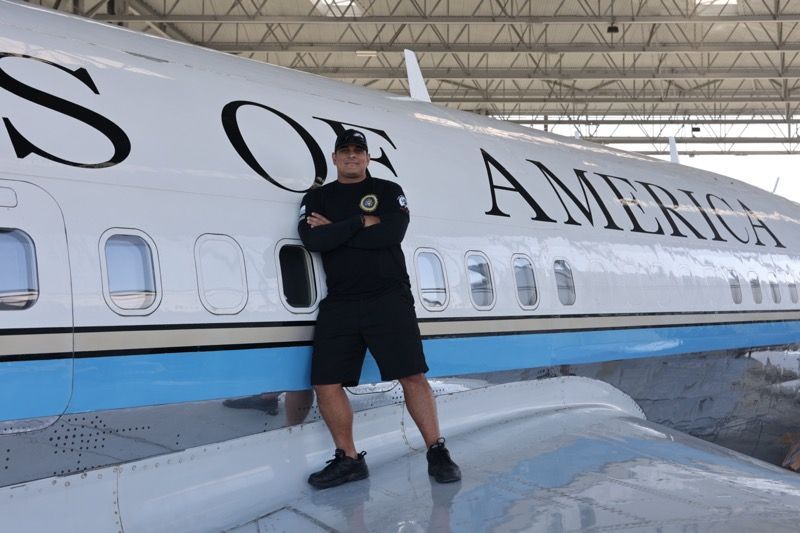 Man in black leaning on the wing of a 