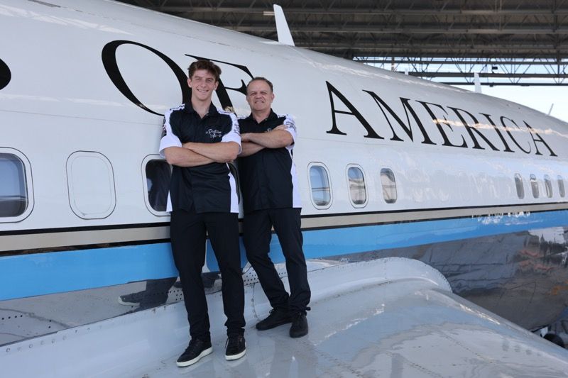 Two men in front of a plane. The plane says 