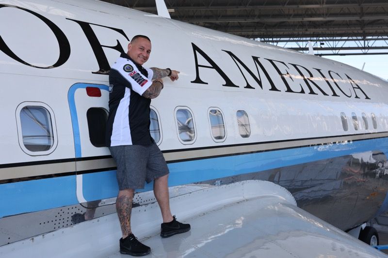 Man poses on the wing of a large white plane with 