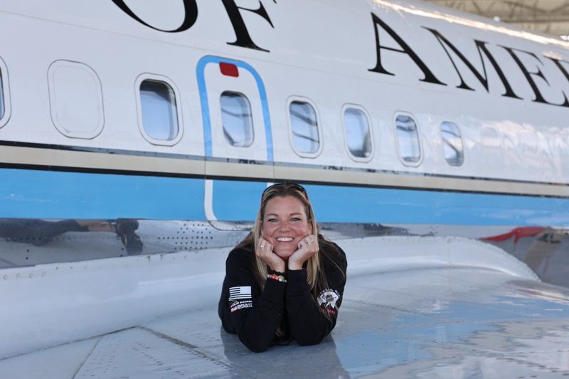 Woman smiles on the wing of a plane, 