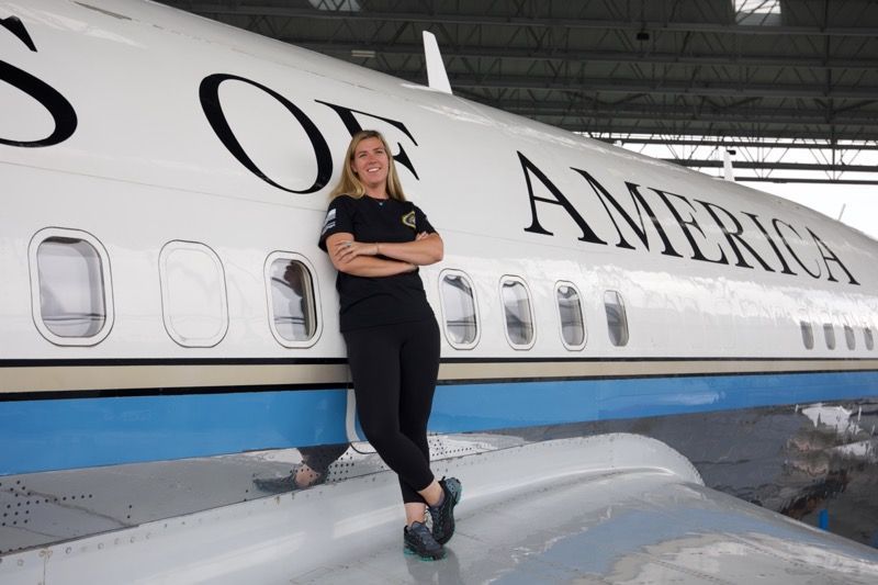 Woman leaning on the side of a white airplane labeled 