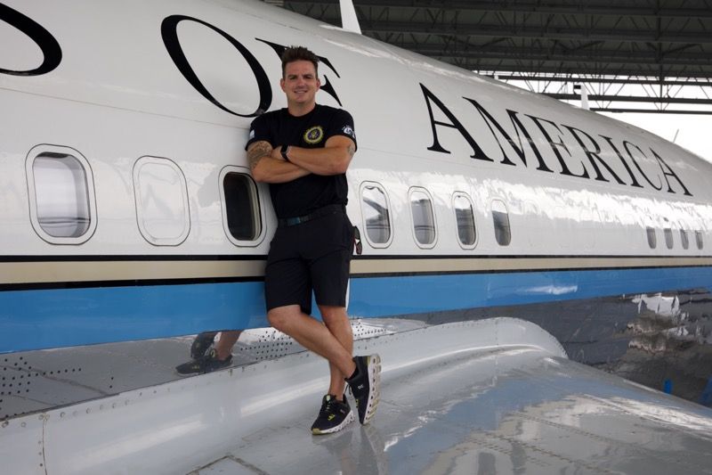 Man in black clothes leans against the side of a plane painted with 