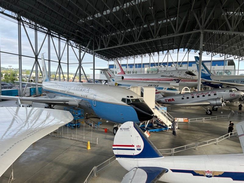 Airplanes displayed inside a large hangar, including a Boeing 707 painted blue and white.