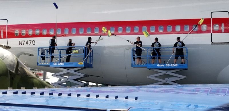 People cleaning an airplane fuselage from elevated platforms.