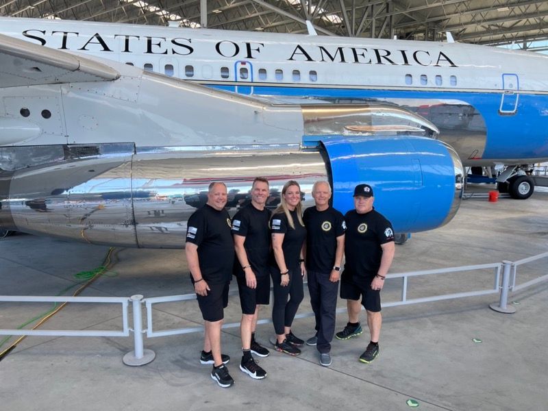Five people pose in front of a blue and white 