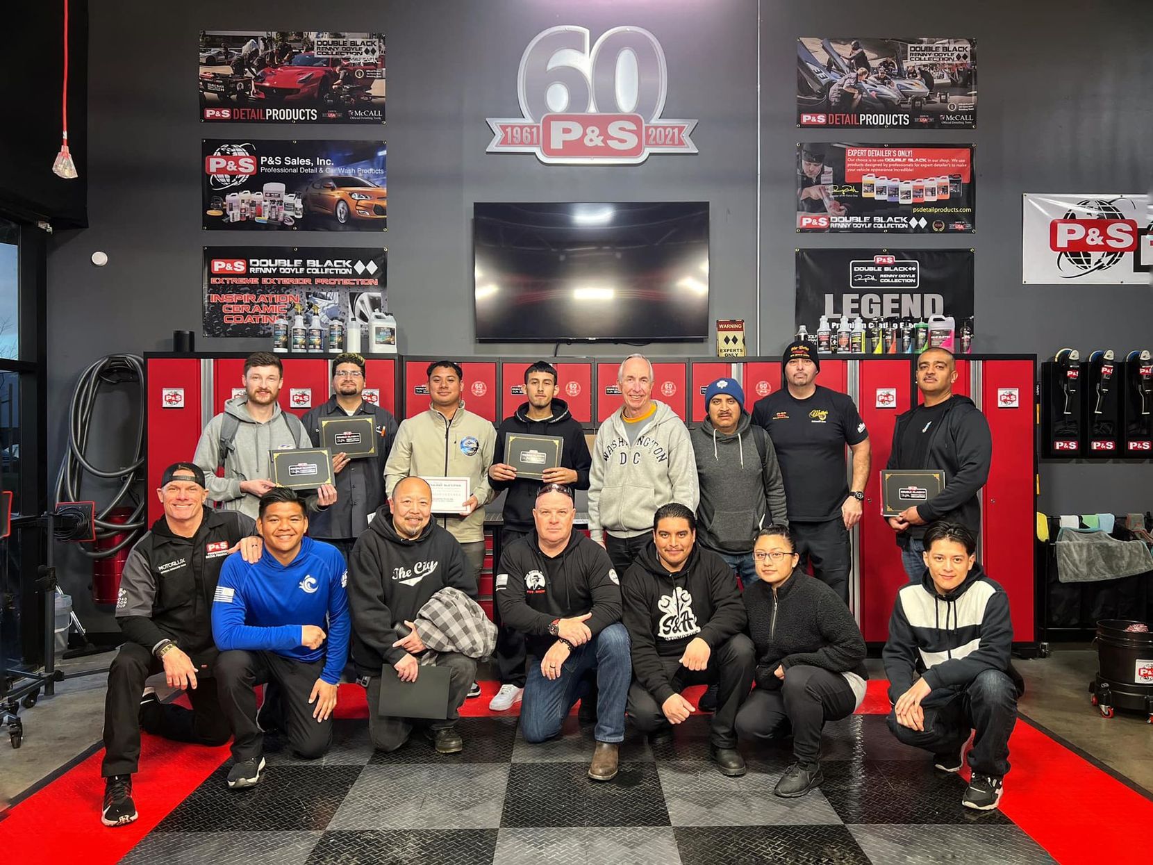 Group of people holding plaques posing inside a shop with 60th anniversary signage.