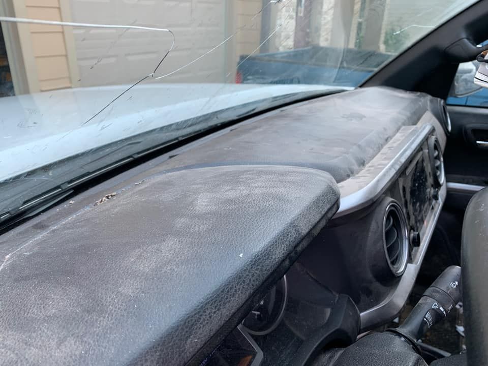 Close-up view of a car's cracked windshield and dusty dashboard.