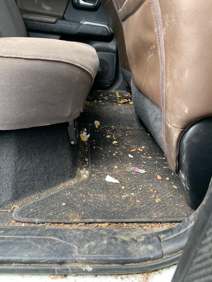 Dirty car interior; brown and tan seats with debris on black floor.
