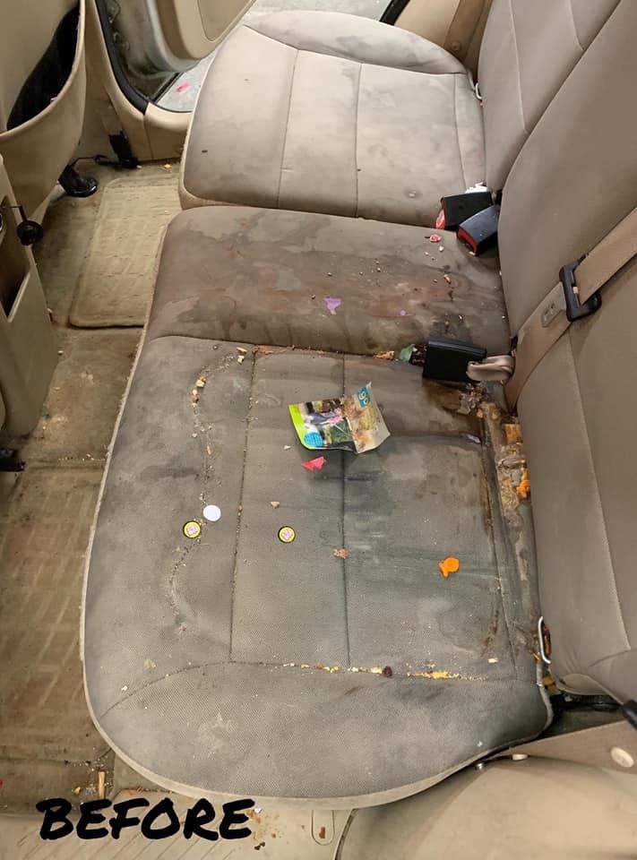 Dirty, stained car backseat with trash and debris;