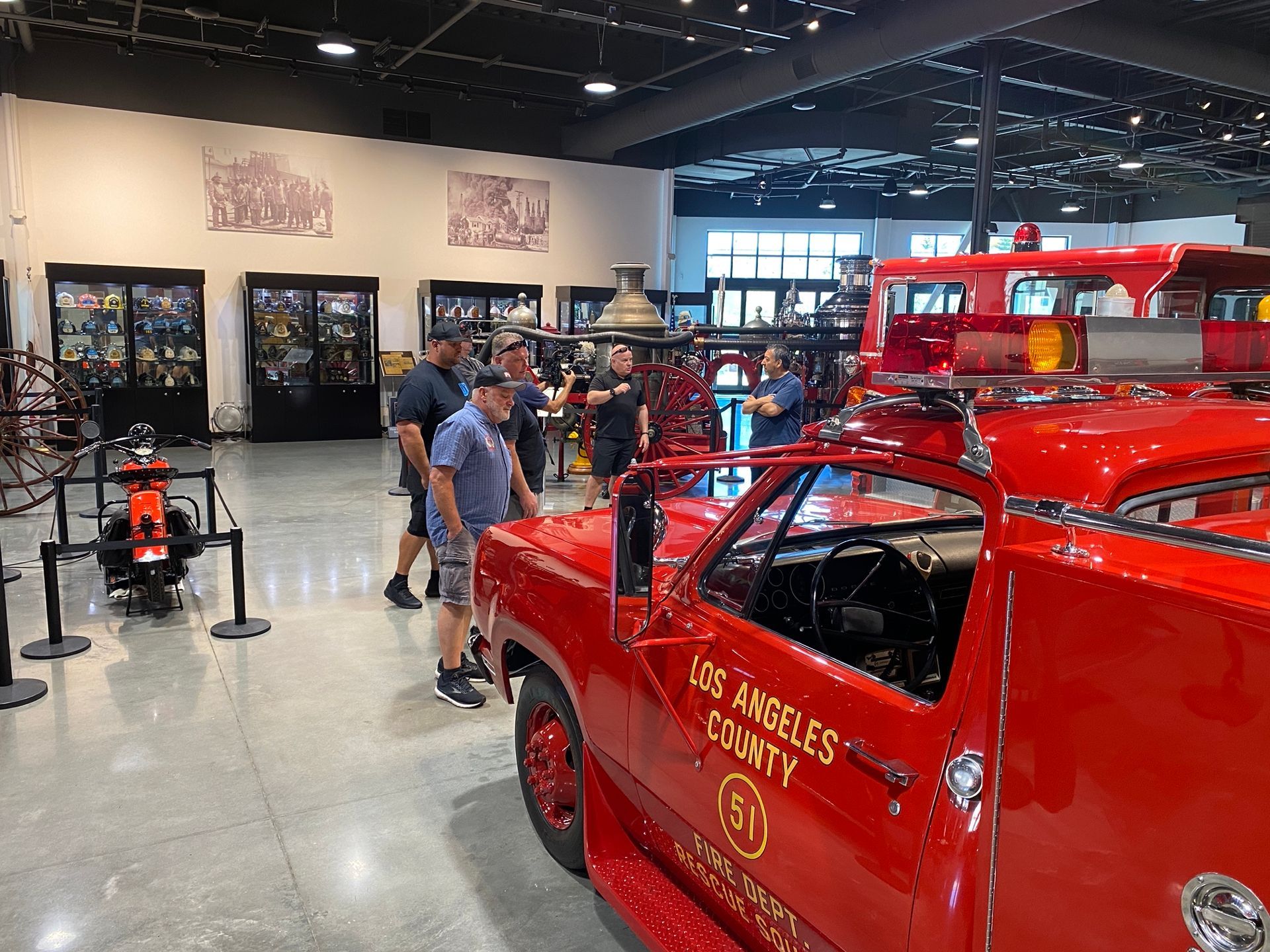 Inside a museum, people admire a bright red Los Angeles County fire truck.