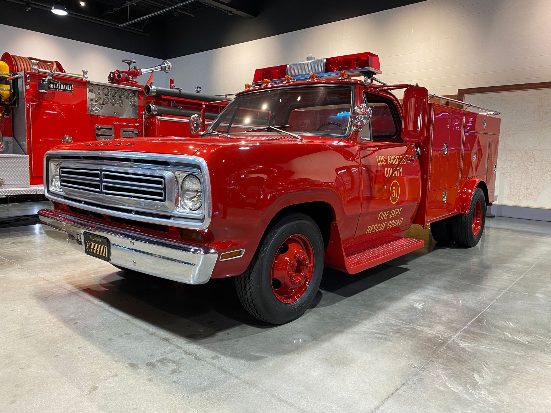 Red vintage fire truck parked indoors, chrome details, emergency lights on roof.
