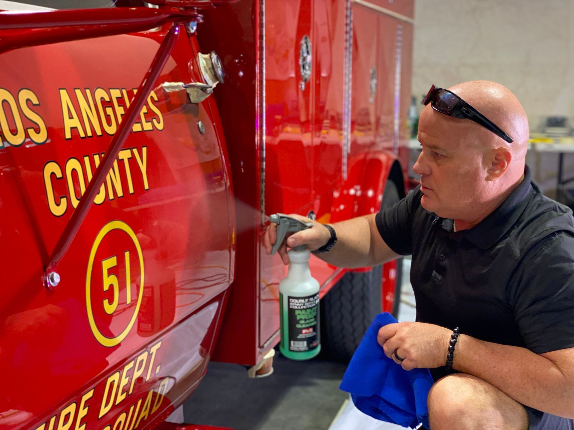 Man spraying and wiping a red fire truck with