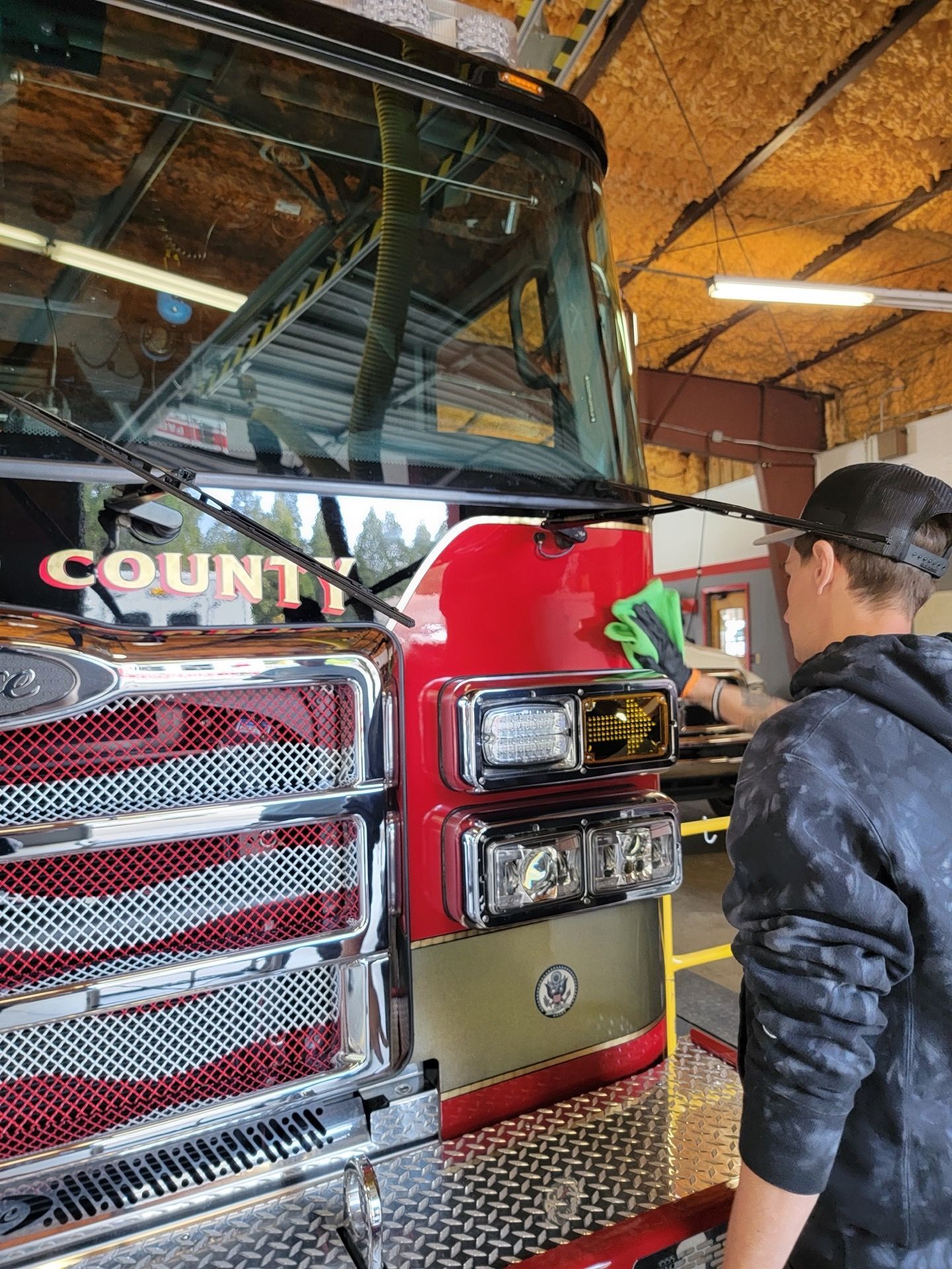 Person cleaning a red fire truck at a fire station.