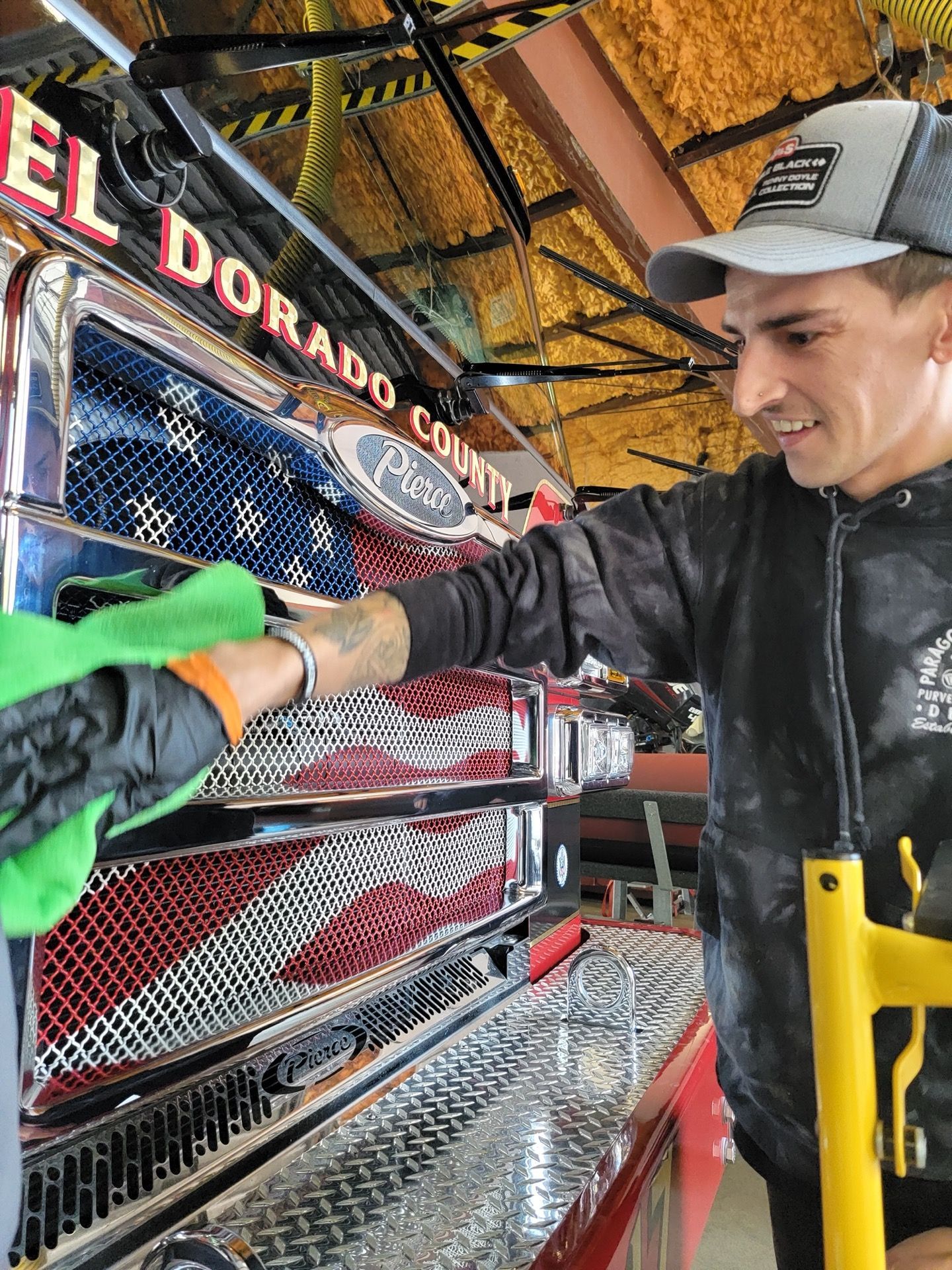 Man cleaning a fire truck, with American flag design. El Dorado County is visible.