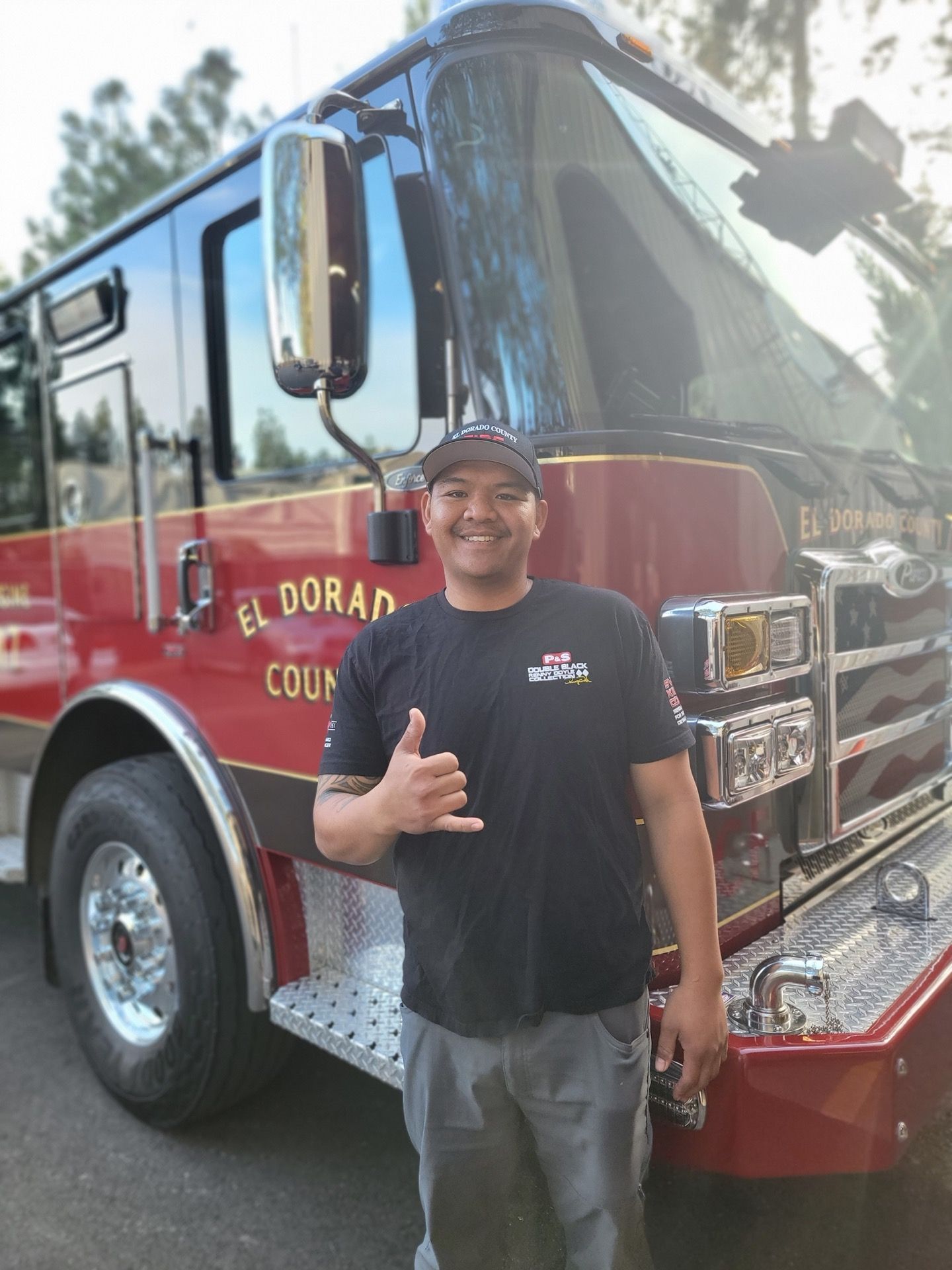 Firefighter smiles, gives shaka, in front of El Dorado County fire truck.