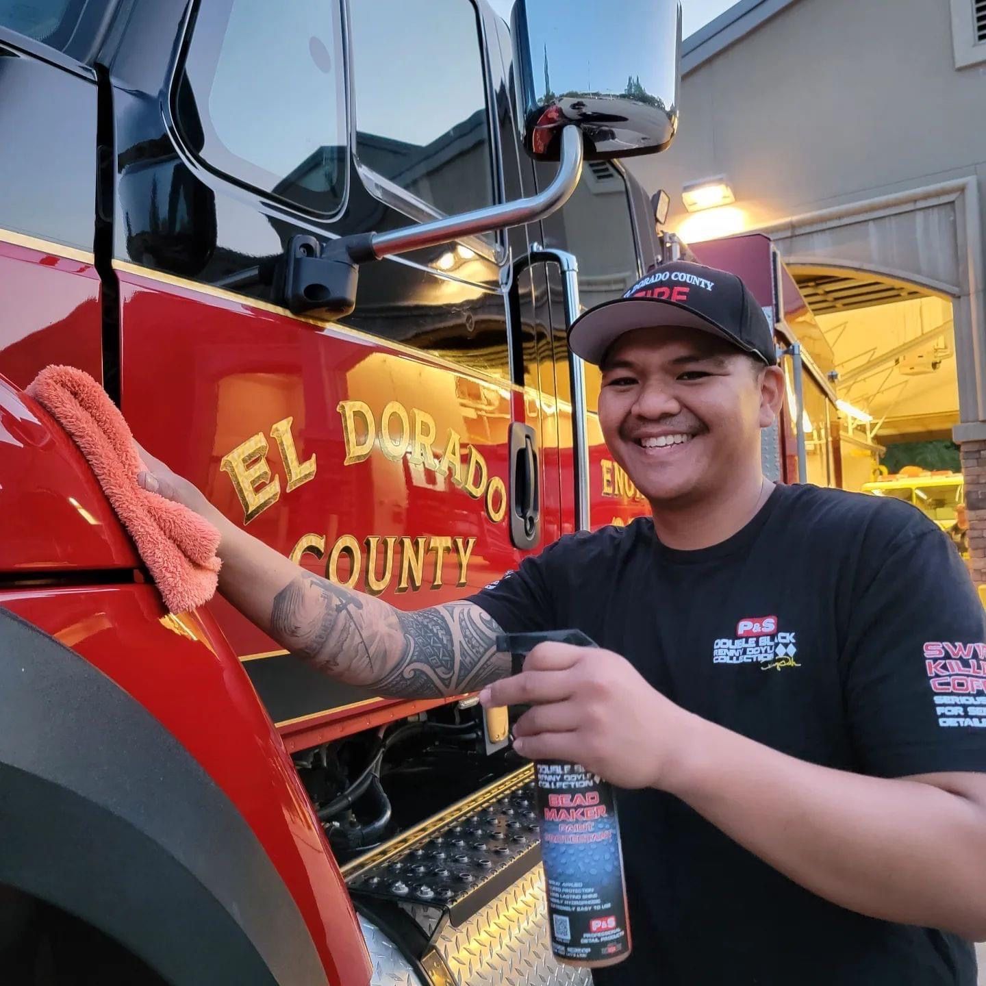 Man cleaning a red fire truck with