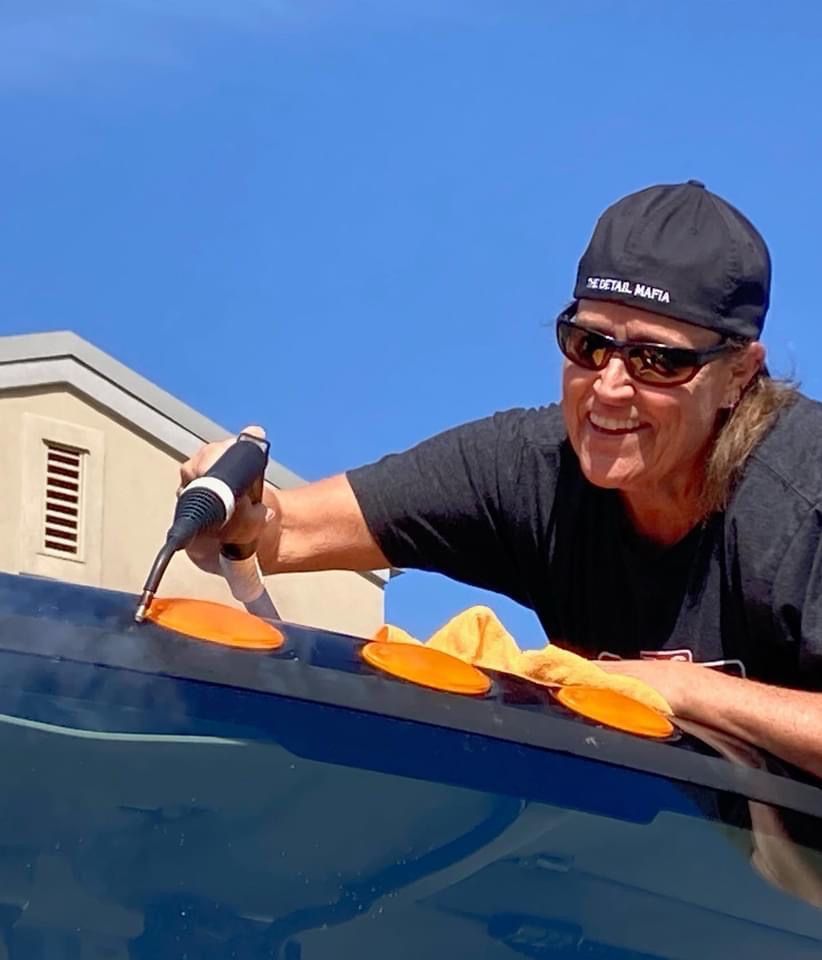 Woman using tools to repair vehicle, outside on sunny day.