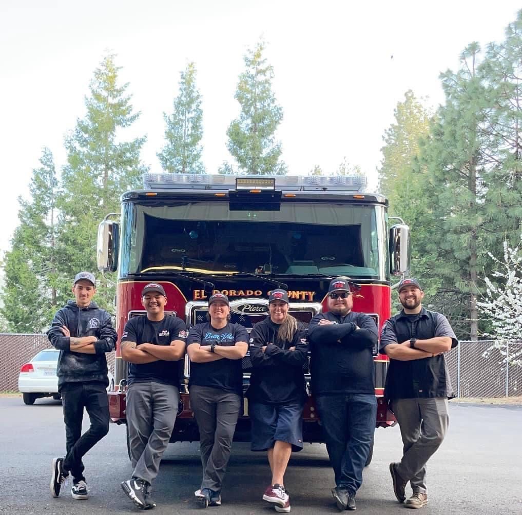 Firefighters stand in front of a red fire truck. El Dorado County, California.