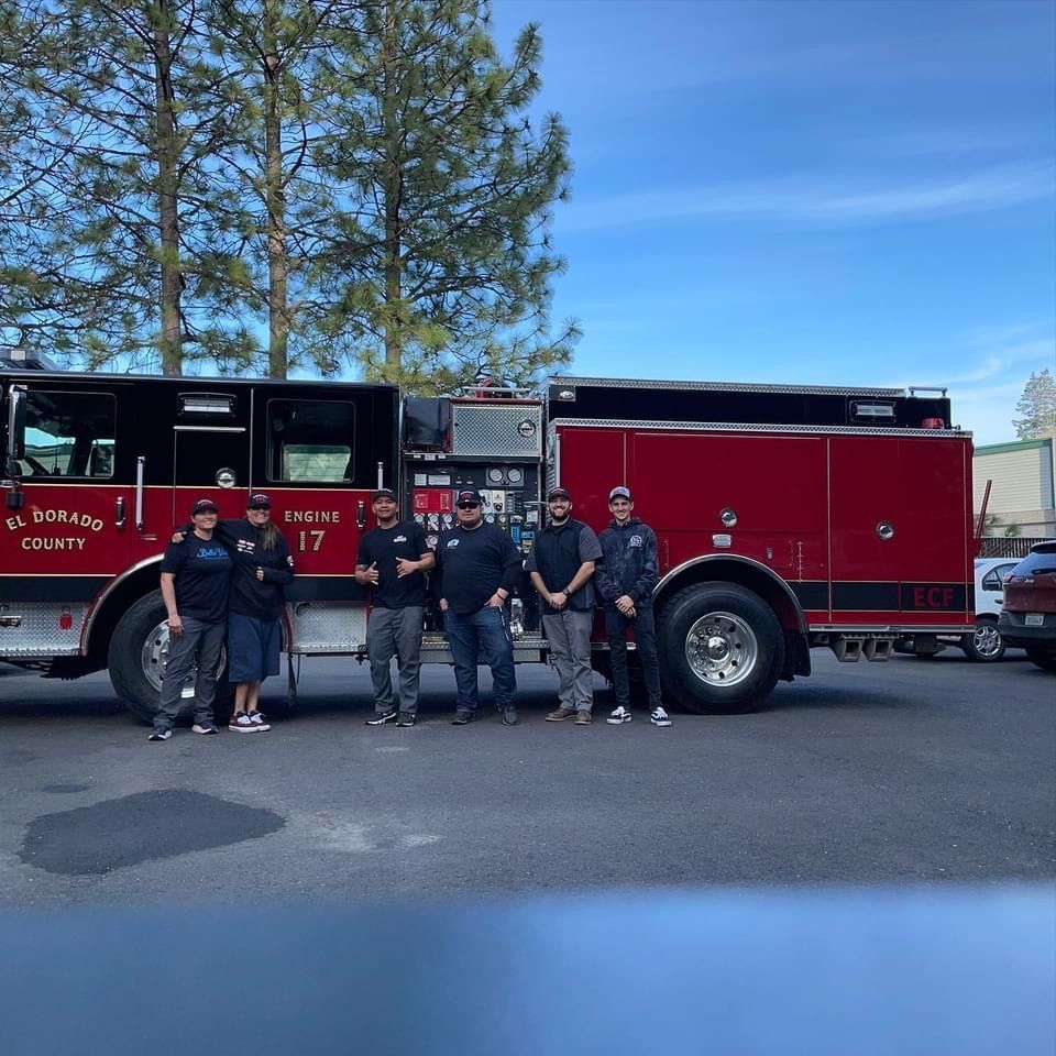 Firefighters in front of a red fire truck. El Dorado County. Day time.