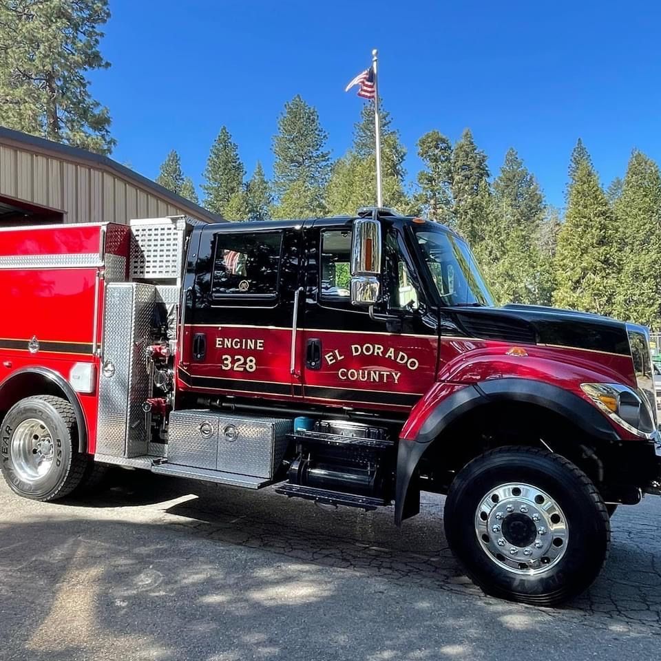 El Dorado County Fire Engine 328 parked near a building, American flag in the background, sunny day.