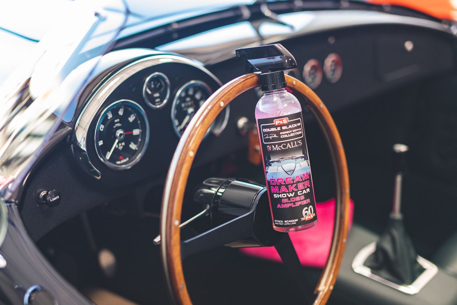 Spray bottle hanging on a classic car steering wheel, dashboard in background.