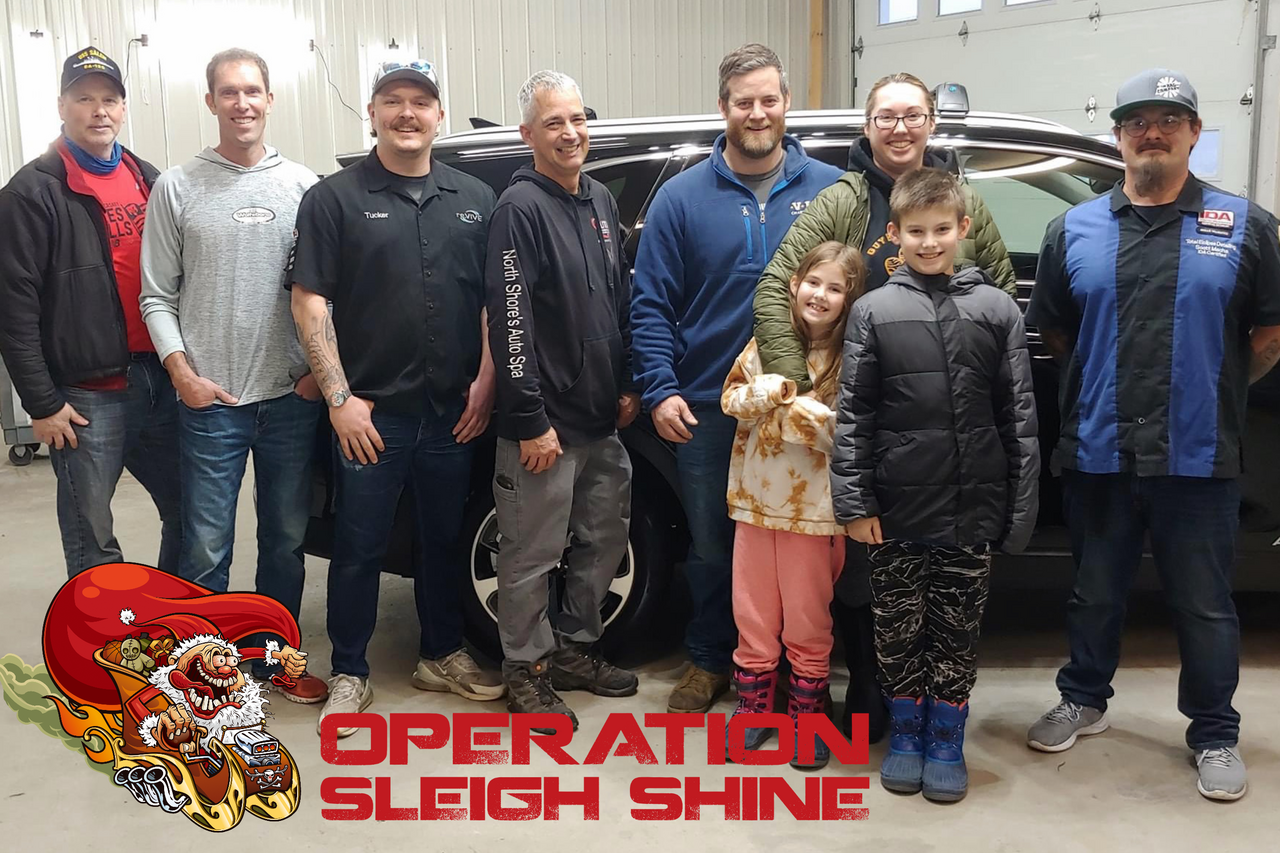 Group of men and children pose near a vehicle,