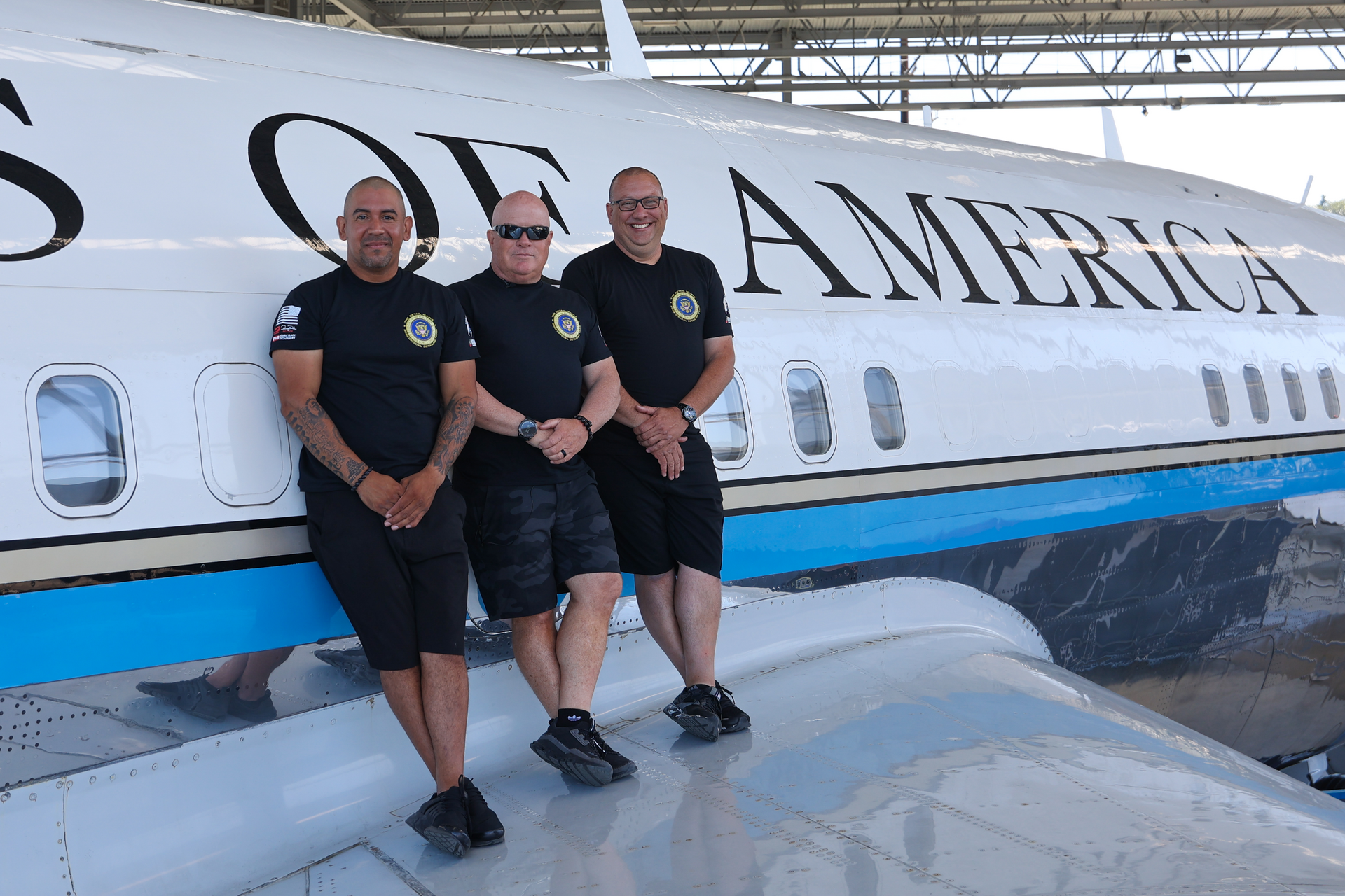 Three men pose in front of a plane with 