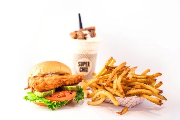 Super chix chicken sandwich french fries, and a custard shake are on a table.