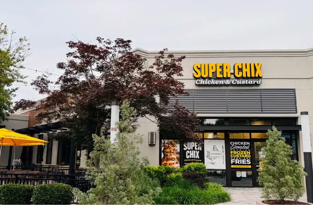 Super Chix restaurant exterior with sign, awning, tree, and shrubbery.