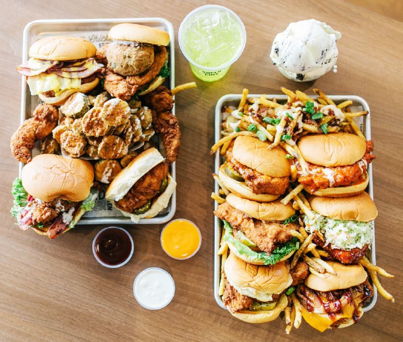 Top down view of several super chix sandwiches with fries and chicken strips.