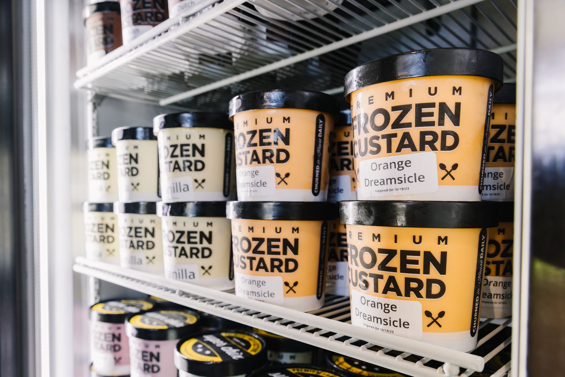 Shelves stocked with premium frozen custard tubs in various flavors, including orange.