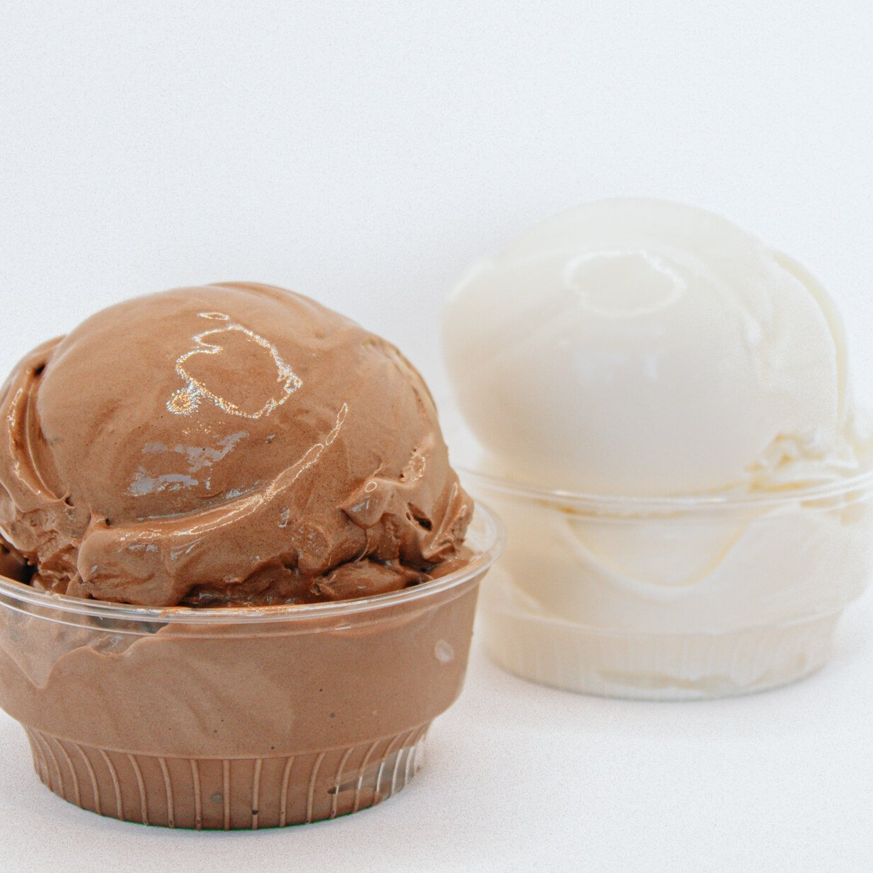 Chocolate and vanilla ice cream scoops in clear plastic cups.