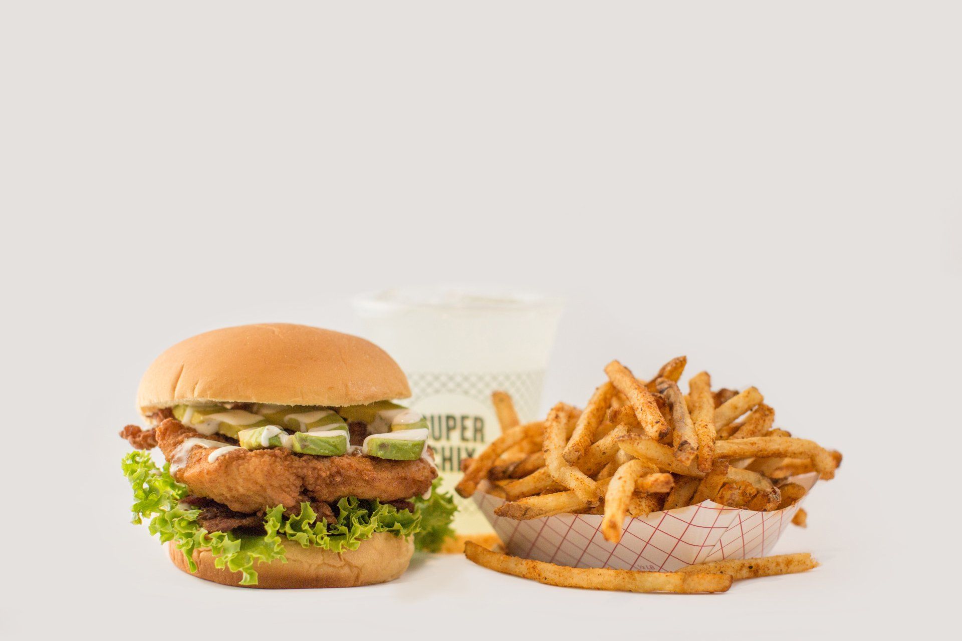 Burger with fries and a drink on a white background.