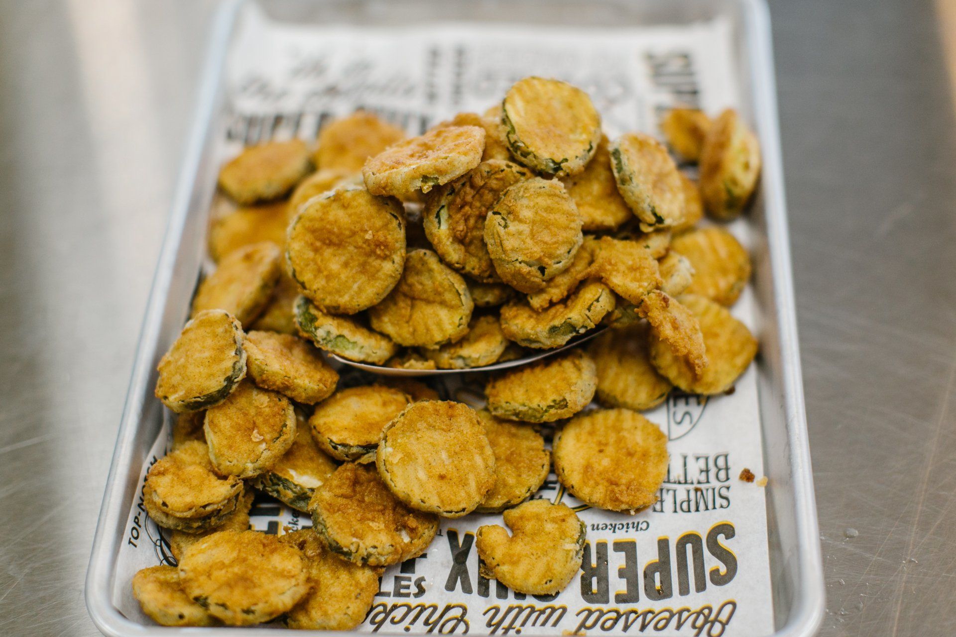 Fried pickle slices on a tray lined with newspaper.