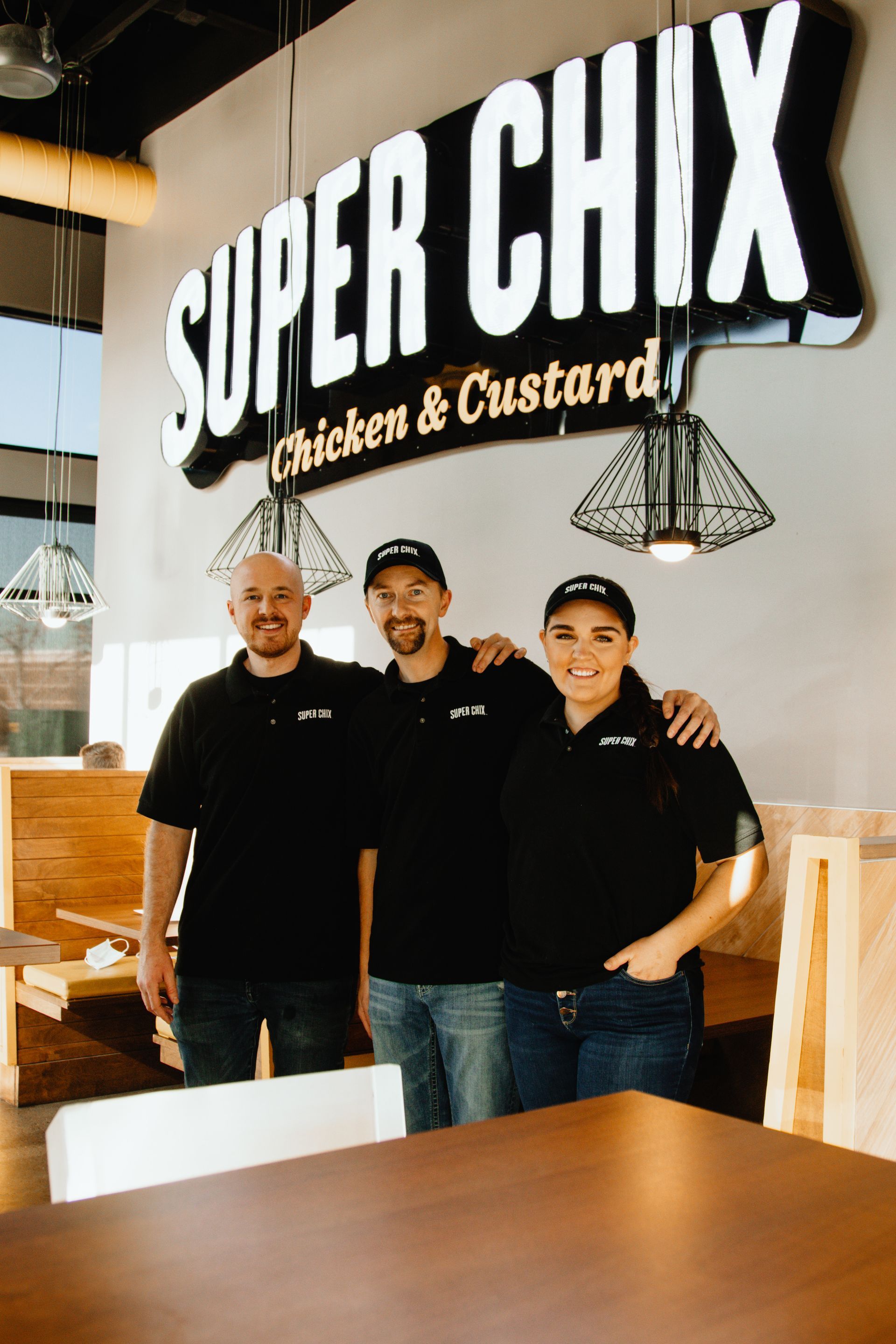 Three people in black shirts pose under a 