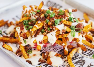Super chix loaded seasoned fries with bacon bits green onions and queso cheese.