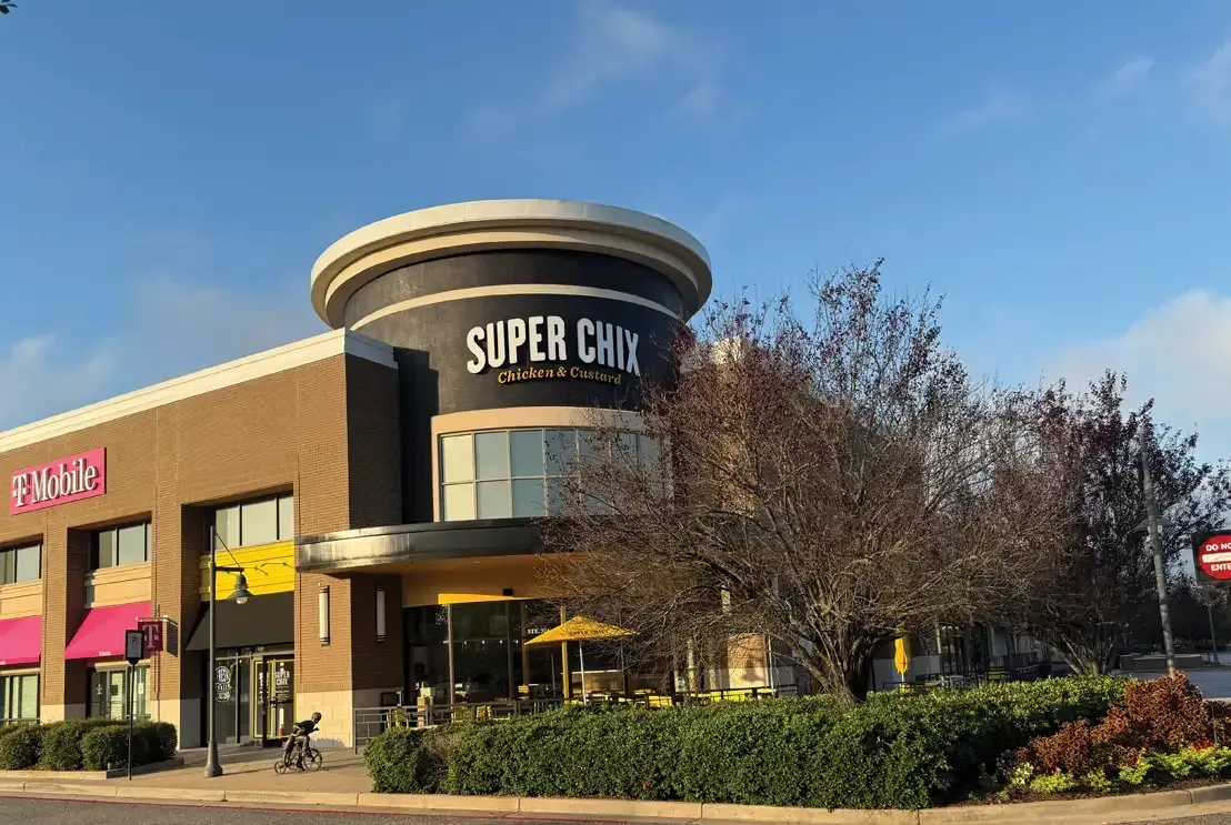 Super Chix restaurant with a round, black and white structure, sunny exterior, and T-Mobile next door.